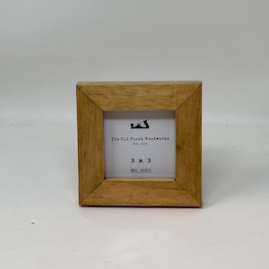 May include: A small, wooden picture frame with a light brown finish. The frame is 3 inches by 3 inches and has a label that reads "The Old Plank Woodworks Est. 2013" and "3 x 3 SKU 30605".