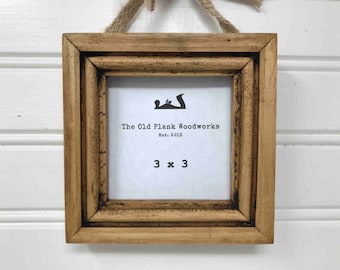 May include: A small, rustic wooden picture frame with a white mat and a black and white logo that reads "The Old Plank Woodworks Est. 2013" and "3 x 3".