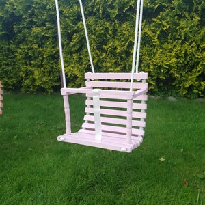 Wooden baby swing with engraved message option on the back of the swing in pale pink color made of birch wood.