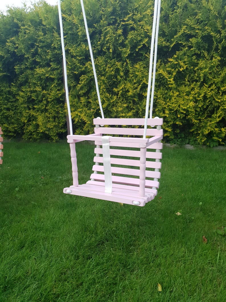 Wooden baby swing with engraved message option on the back of the swing in pale pink color made of birch wood.
