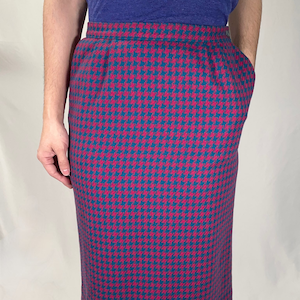 May include: A knee-length skirt with a houndstooth pattern in shades of teal and pink.