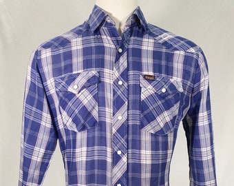 May include: A blue and white plaid long-sleeve button-up shirt with a brown "Wrangler" logo on the left chest pocket.