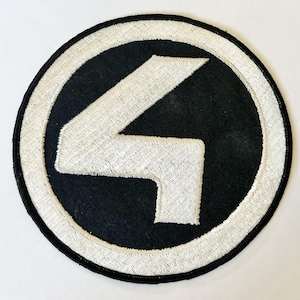 Pode incluir: Um emblema bordado circular com fundo preto e um grande número quatro branco centralizado. O design é envolvido por uma borda circular branca espessa e finalizado com uma borda costurada em preto, criando um emblema de alto contraste.