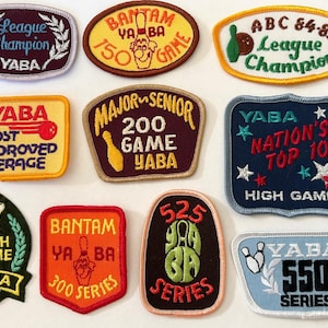 Op de afbeelding: Een verzameling van tien geborduurde YABA-bowlingpatches in verschillende vormen en kleuren, met teksten zoals League Champion, Bantam 150 Game, ABC 84-85, Most Improved Average, Major Senior 200 Game, Nation's Top 10, High Game, 300 Series en 550 Series.