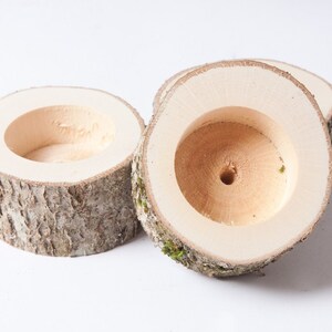Pu&ograve; includere: Tre portacandele in legno realizzati con corteccia d'albero con un centro cavo. I portacandele sono di colore naturale e hanno un aspetto rustico.
