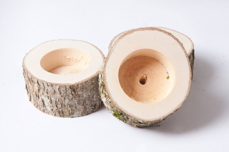 Puede incluir: Tres portavelas de madera hechos de corteza de &aacute;rbol con un centro hueco. Los portavelas son de color madera natural con una textura de corteza rugosa.
