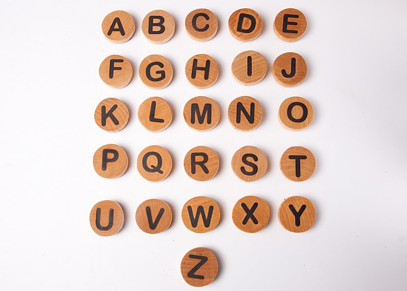 K&ouml;nnte beinhalten: Holzalphatile mit schwarzen Buchstaben auf wei&szlig;em Hintergrund. Die Kacheln sind in alphabetischer Reihenfolge von A bis Z angeordnet.