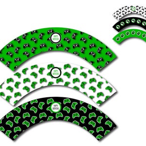 Puede incluir: Envoltorios para cupcakes con temática de videojuegos. Los envoltorios presentan un patrón de mandos de juego negros sobre fondos verdes, blancos y negros. Cada envoltorio tiene una etiqueta circular que dice "Happy Birthday".