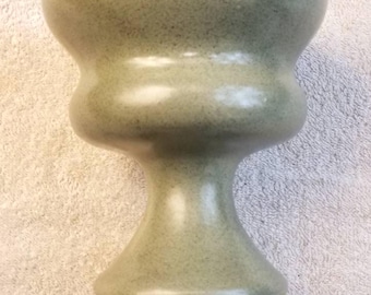 May include: A light green ceramic vase with a bulbous midsection and a flared base. The vase has a speckled texture and measures approximately 10 inches in height.