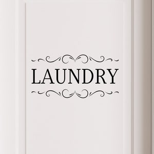 May include: White door with a black vinyl decal that says "LAUNDRY" with decorative swirls above and below the word.