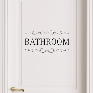 May include: White door with a black vinyl decal that says "BATHROOM" with decorative swirls above and below the text.