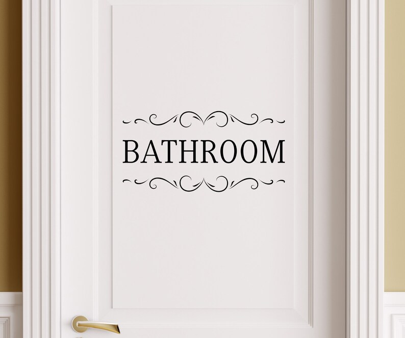 May include: White door with a black vinyl decal that says "BATHROOM" with decorative swirls above and below the text.