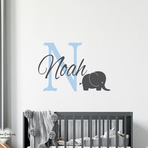 May include: A light blue letter N with the name Noah written in cursive script, a gray elephant silhouette, and a crib in the background.