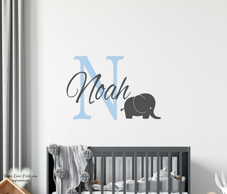 May include: A light blue letter N with the name Noah written in cursive script, a gray elephant silhouette, and a crib in the background.