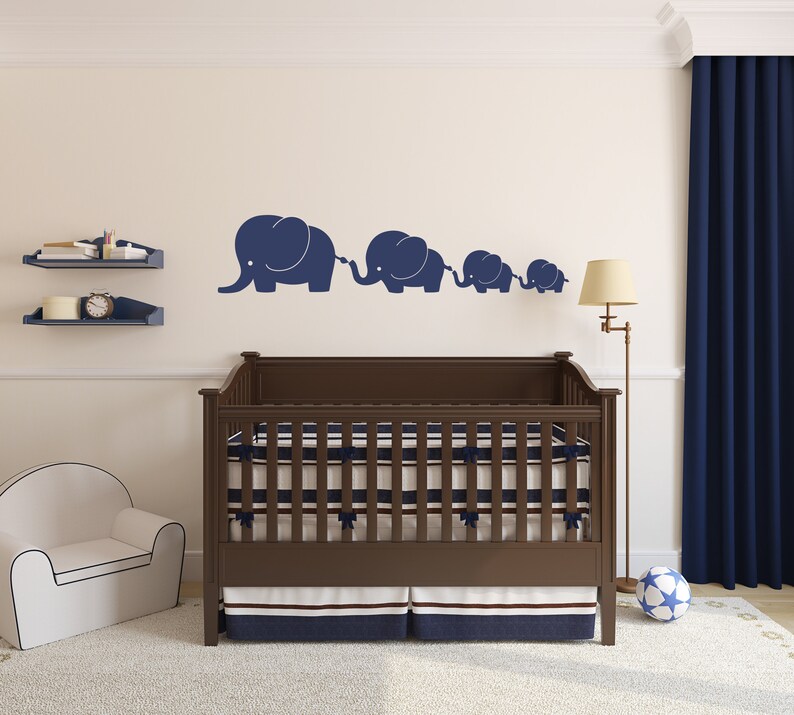 Peut inclure: Un lit b&eacute;b&eacute; en bois brun avec un matelas ray&eacute; blanc et bleu marine et une jupe ray&eacute;e bleu marine et blanche. Le lit b&eacute;b&eacute; est dans une chambre d'enfant avec un mur blanc et un rideau bleu. Il y a quatre silhouettes d'&eacute;l&eacute;phants bleu marine sur le mur.