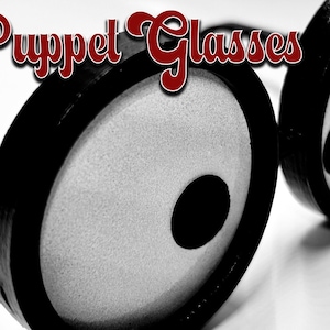 Puede incluir: Gafas redondas en blanco y negro con lentes grandes y redondos. Las gafas son de plástico y tienen un diseño sencillo. El texto "STL FILE" es visible en la esquina inferior derecha de la imagen.