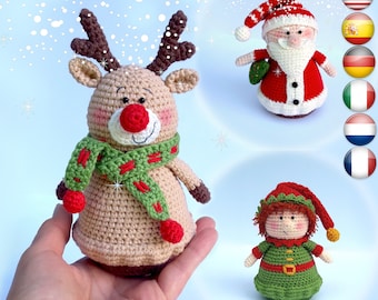 Könnte beinhalten: Handgefertigte Weihnachtsornamente aus Häkelarbeit. Das Bild zeigt ein Rentier mit roter Nase und grünem Schal, den Weihnachtsmann und einen Elf. Die Ornamente sind beige, rot, grün und weiß. Der Hintergrund ist hellblau mit weißen Glitzer.