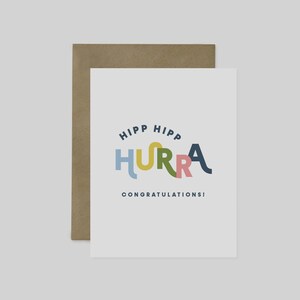 May include: A white greeting card with the words "HIPP HIPP HURRA CONGRATULATIONS!" in colorful, playful lettering. The card is paired with a brown envelope, perfect for sending well wishes.