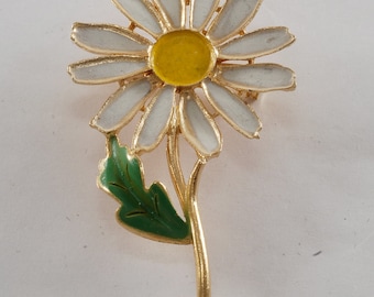 Peut inclure: Broche en forme de marguerite dorée, avec des pétales blancs et un cœur jaune, ainsi qu'une feuille verte. Cet accessoire floral est idéal pour ajouter une touche de style inspirée de la nature à n'importe quelle tenue.