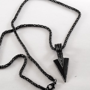 May include: A black chain necklace with a black arrowhead pendant.