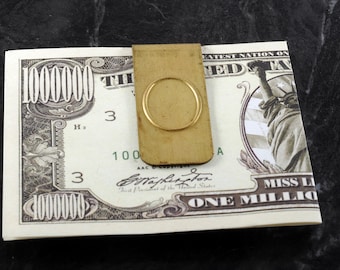 May include: A gold money clip with a rounded oval opening. The money clip is on top of a one million dollar bill with the text "The Greatest Nation on Earth" and a depiction of the Statue of Liberty.