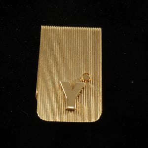 May include: Gold-toned money clip with a raised letter 'Y' and a small circle on the top.