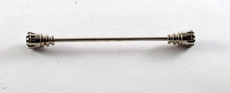 May include: A silver tie bar with a decorative design on each end.