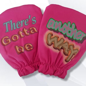 May include: A pair of pink oven mitts with the text "There's Gotta be another way" printed on them. The text is in a colorful, graffiti-style font.