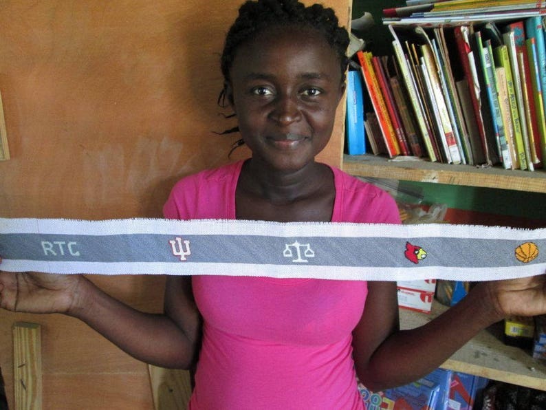 May include: A person is holding a grey and white fabric strip with the text "RTC" and a stylised "Psi" symbol, along with a scale, a red cardinal, and a basketball.
