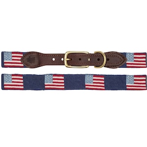 May include: A dog collar and matching leash featuring a navy blue background with repeating American flags in red, white, and blue. The collar has a brown leather strap and a gold-colored buckle.