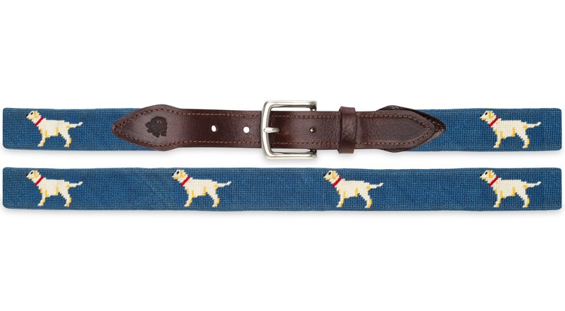 May include: A blue and brown woven belt with a silver buckle. The belt features a repeated pattern of white Labrador Retrievers.