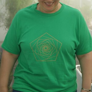 Può includere: Una maglietta verde con un design geometrico dorato a forma di rosa.