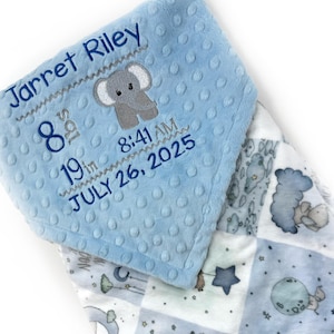 May include: A baby blanket with a blue, textured top and a patterned bottom. The top features the name "Jarret Riley", an elephant graphic, and birth details: 8th, 19th, 8:41 AM, July 26, 2025. The bottom has a patchwork design with stars and moons.