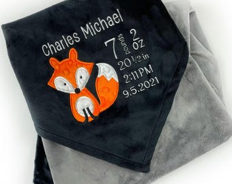 May include: A dark gray and light gray baby blanket with embroidered details. The blanket features a cartoon fox and the name "Charles Michael" with birth details: 7 pounds 2 oz, 20 1/2 in, 2:11 PM, 9.5.2021.