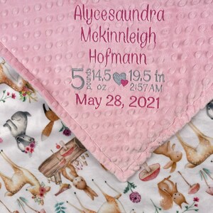 May include: Pink and white baby blanket with a deer and floral print. The pink side has embroidered text: Alycesaundra Mckinleigh Hofmann 5 pounds 14.5 oz 19.5 in 2:57 AM May 28, 2021.