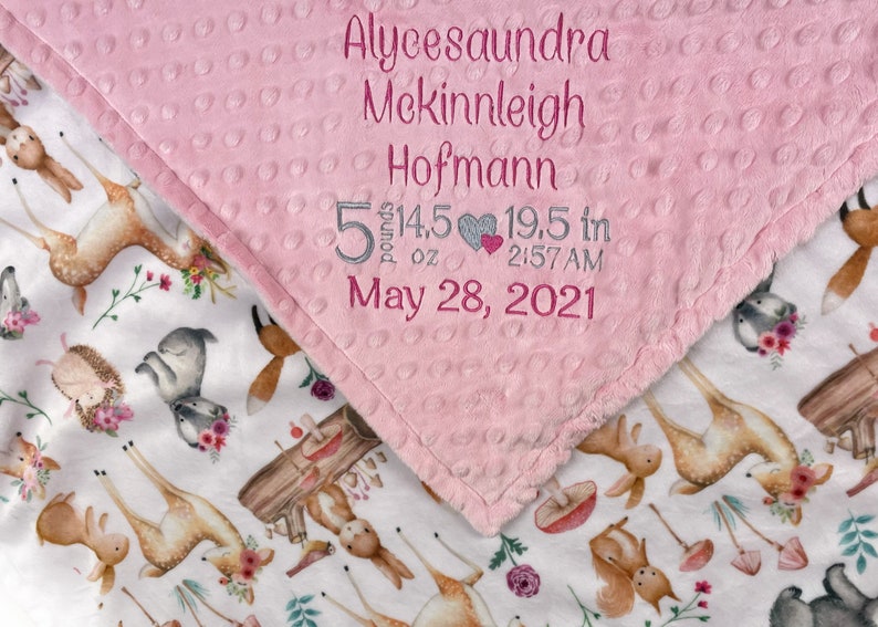 May include: Pink and white baby blanket with a deer and floral print. The pink side has embroidered text: Alycesaundra Mckinleigh Hofmann 5 pounds 14.5 oz 19.5 in 2:57 AM May 28, 2021.