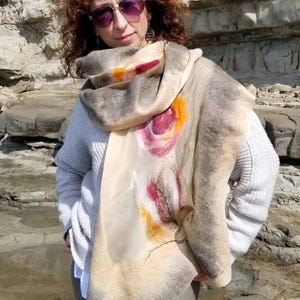 Woman wrapped in luxurious beige and khaki shawl made of merino wool and silk, showing elegant texture.