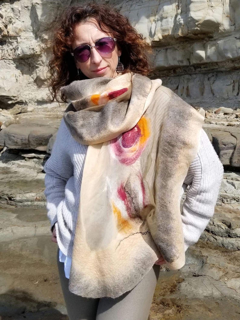 Woman wrapped in luxurious beige and khaki shawl made of merino wool and silk, showing elegant texture.