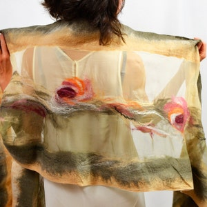 May include: A beige and green silk scarf with a floral design. The scarf has a sheer, translucent texture and features three pink, orange, and white flowers.