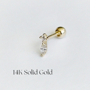 Könnte beinhalten: Ein goldener Ohrring mit einem kleinen, klaren, marquiseförmigen Edelstein. Der Ohrring ist aus 14 Karat massivem Gold gefertigt und hat einen Steckerverschluss.