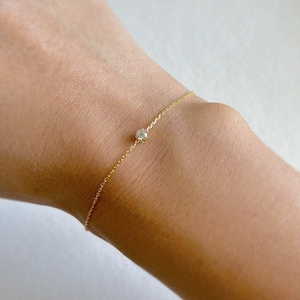May include: A delicate gold chain bracelet with a single, small, round diamond.