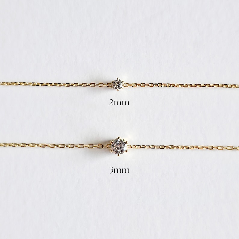 May include: Two gold chains with a single clear gemstone on each. The top chain has a 2mm stone and the bottom chain has a 3mm stone.