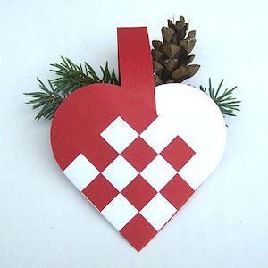 May include: Red and white heart-shaped ornament with a checkered pattern. The ornament is made of paper and has a loop at the top for hanging.
