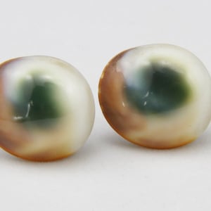 May include: A pair of round, iridescent earrings with a green and brown swirl pattern.