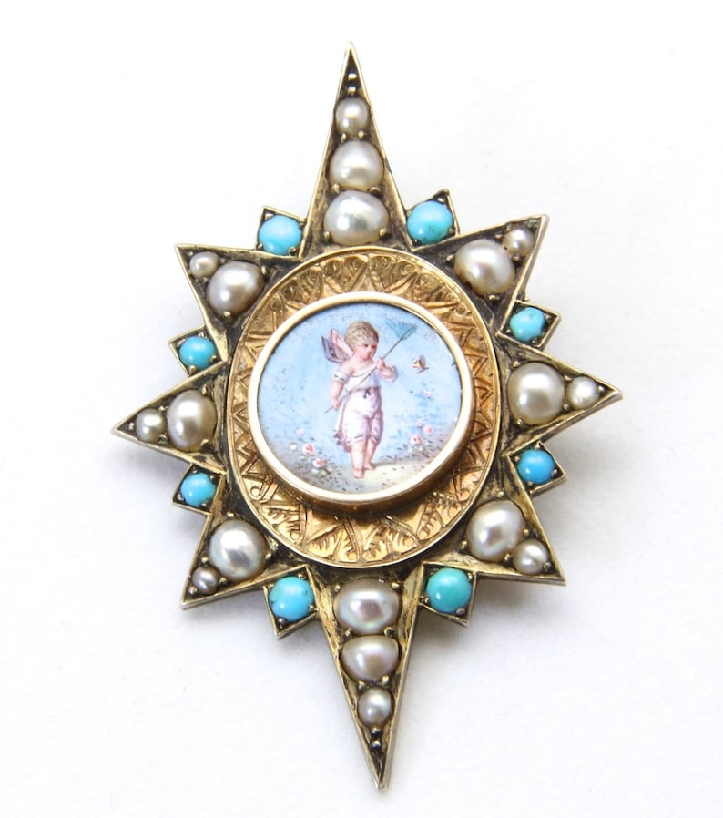 May include: A gold-toned starburst brooch featuring a central oval miniature painting of a cherub. The brooch is adorned with pearls and turquoise stones. The brooch has a detailed, ornate design.