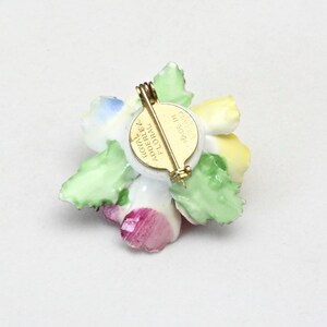 Peut inclure: Une broche en porcelaine en forme de fleur avec un motif floral jaune, rose, bleu et vert. Le dos de la broche a une &eacute;pingle dor&eacute;e et une &eacute;tiquette qui indique "Royal Adderley Floral Made in England".