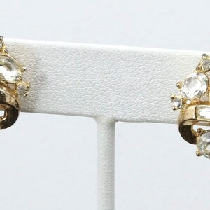 May include: A pair of gold tone clip-on earrings with clear rhinestone accents.