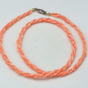 May include: A coral necklace with a gold clasp. The necklace is made of small, rectangular coral beads.