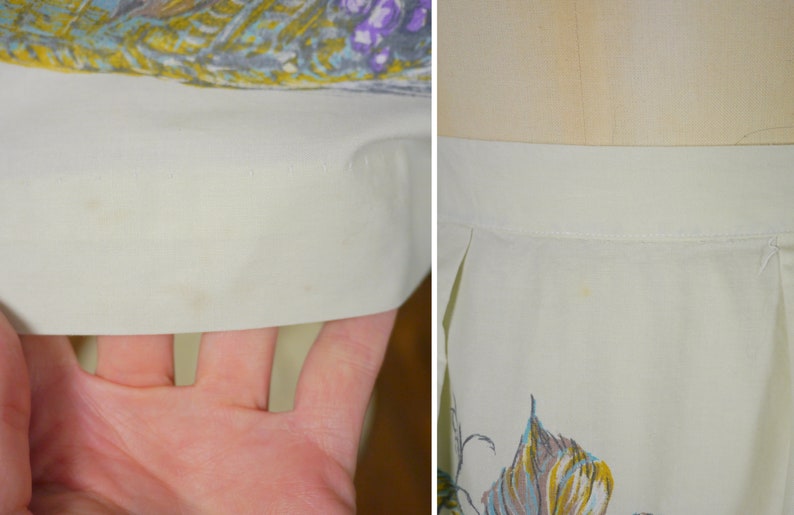 May include: Close-up of a white skirt with a floral print. The skirt has a waistband and pleats. There are some light stains on the fabric.