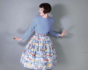 May include: A woman wearing a blue and white striped long-sleeved shirt and a full skirt with a colorful print of various objects. The skirt is gathered at the waist and falls to just below the knee.